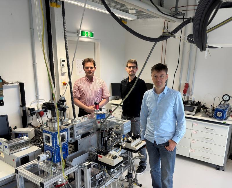 Die Leipziger Autoren des Übersichtsartikels: Prof. Dr. Jonas Warneke (l.), Dr. Markus Rohdenburg (Mitte) und Dr. Harald Knorke (r.) neben einem Instrument zur Synthese dünner Schichten mit gasförmigen geladenen Molekülbruchstücken. (Bild: Ziyan Warneke)